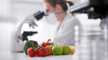 Scientist in lab with fruit and vegetables in foreground