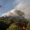 Image: A fire-fighting helicopter drops water over a forest fire in Nea Makri village northeast of Athens