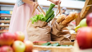 Woman picking heavy shopping bags in food store