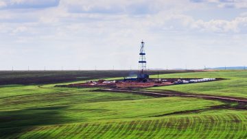 Drilling rig among green fields, a top view