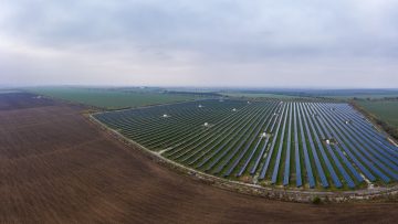 Fly over a renewable solar power plant with sun in Ukraine