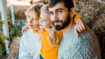 adult male farmer looking at camera while his family sitting beh