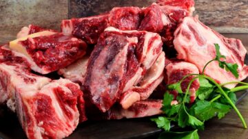Raw meat with bone on clay plate and brown stone background.Raw meat with beef bone. Beef bone selection for soup