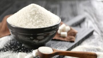 Kitchenware with white sand and lump sugar on black wooden backg