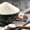 Kitchenware with white sand and lump sugar on black wooden backg