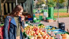 Girl buys fruit and sniffs apple at street market