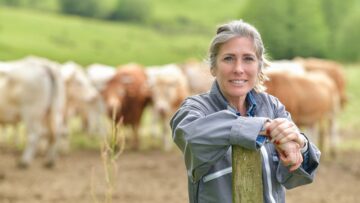 Portrait of a smiling cattlewoman standing beside her cows