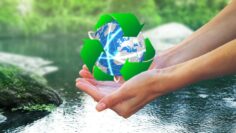 Clear natural water in woman hands on beautiful landscape background.