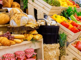 Vibrant farmers market display featuring fresh produce, baked goods in wooden crates