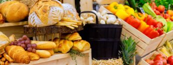 Vibrant farmers market display featuring fresh produce, baked goods in wooden crates