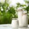 Glass and bottles of fresh milk on table outdoors