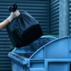 Volunteer puts plastic trash bag into the bin