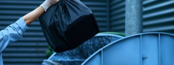 Volunteer puts plastic trash bag into the bin