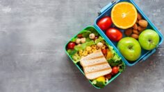 Healthy lunch to go. Fruits and vegetables packed in lunch box. Healthy eating concept. View from above with copy space.