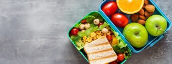 Healthy lunch to go. Fruits and vegetables packed in lunch box. Healthy eating concept. View from above with copy space.